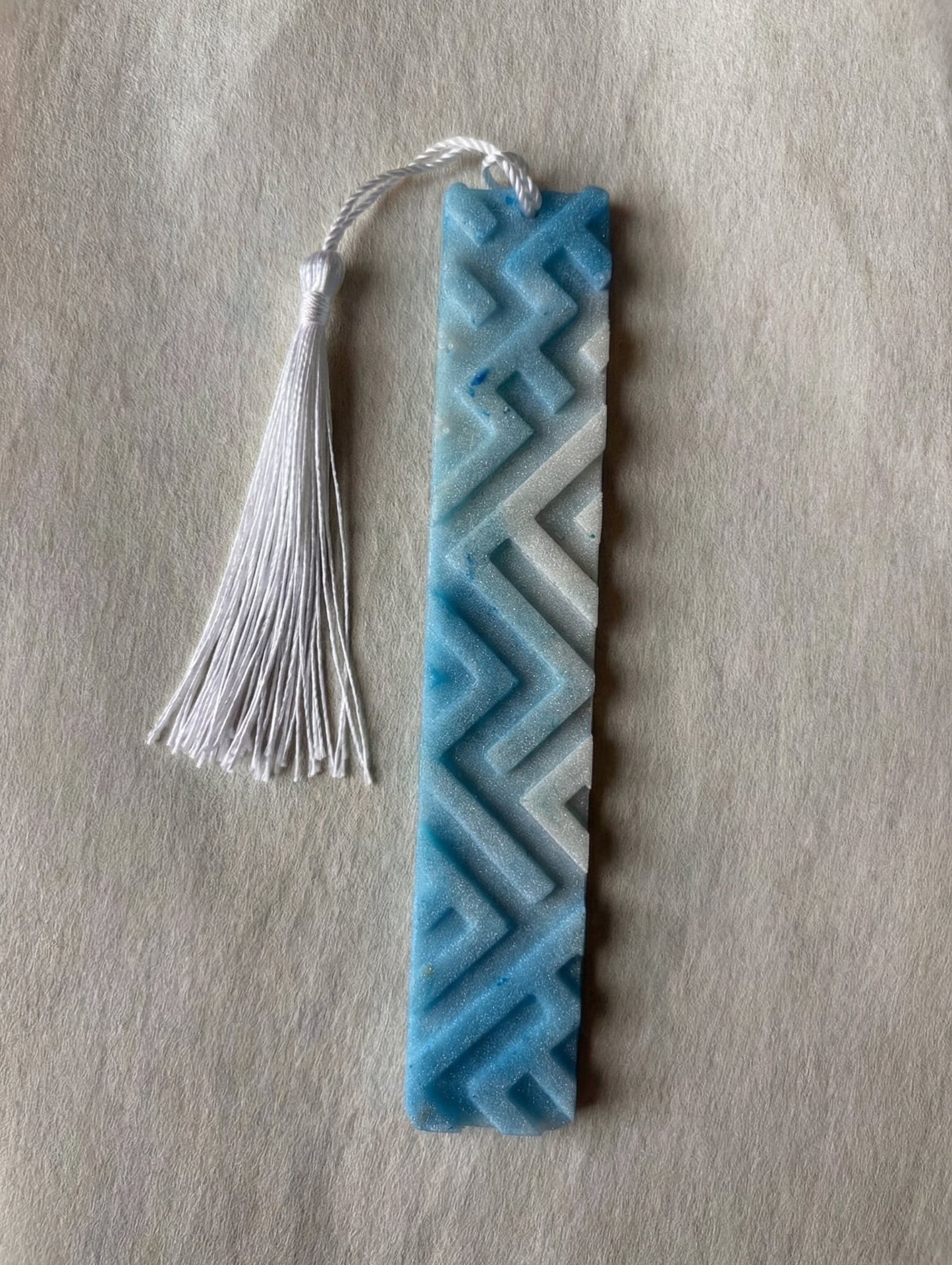 Decorative bookmark with geometric pattern and tassel on a textured surface